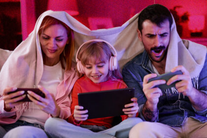 Young family sitting on sofa, all using phones and looking excited.