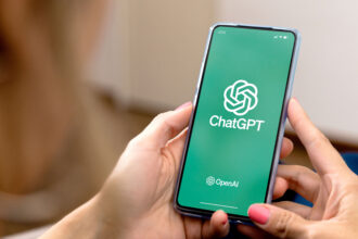 Woman using a mobile phone with ChatGPT on the screen.