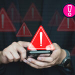 A person holding a phone looking at a scam text with warning signs around