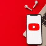 YouTube logo on a phone next to a PC and earbuds