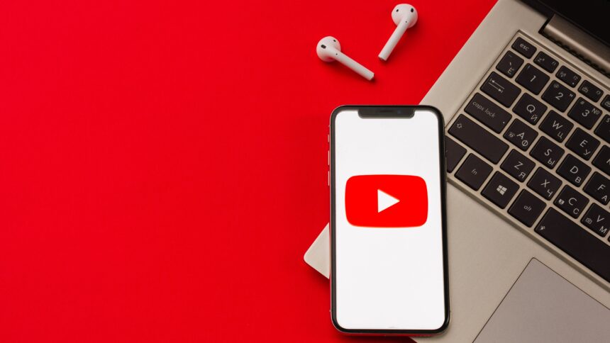 YouTube logo on a phone next to a PC and earbuds