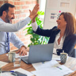 Two people high fiving in a business meeting.