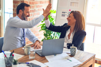 Two people high fiving in a business meeting.
