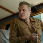 A still from The Waterfront showing Holt McCallany driving a boat