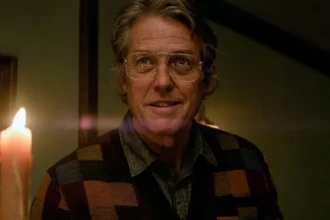 Hugh Grant holds a lit candle in Heretic