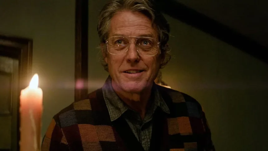 Hugh Grant holds a lit candle in Heretic