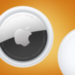 Two Apple AirTags on an orange background