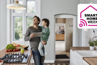 Man using tablet to control smart lights in kitchen while holding child
