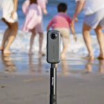 Akaso 360 camera attached to a selfie stick, filming a family on a beach