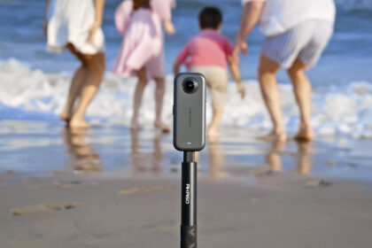 Akaso 360 camera attached to a selfie stick, filming a family on a beach