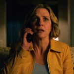 Carol answers her phone in fear while sitting on her couch