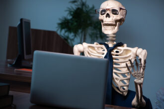 Skeleton of an office worker waiting for their laptop to boot