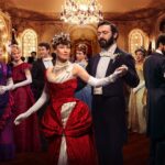 The cast of The Gilded Age look at each other across a ballroom