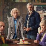 Helen Mirren, Pierce Brosnan, Ben Kingsley and Celia Imrie sit around a table with a slice of cake that has a knife in it at the center