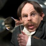 Professor Flitwick holds a speaker up to his mouth
