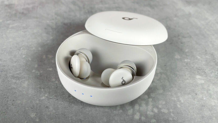 The Soundcore Sleep A30 earbuds are in their charging case. The three indicator lights on the front of the case are lit up white.