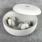 The Soundcore Sleep A30 earbuds are in their charging case. The three indicator lights on the front of the case are lit up white.
