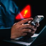 Person with warning notification and spam message icon on mobile phone