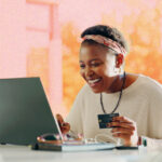 A woman looking happy whilst online shopping on a laptop.