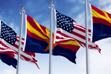 Flags of Arizona and United States waving in the wind on a clear day