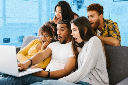 A group of young people sitting on a sofa around a laptop screen, all looking shocked and surprised.