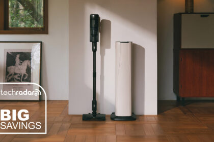Roborock H60 Hub Ultra stick vacuum cleaner standing against a wall, next to its docking station.