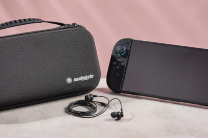 The Nintendo Switch 2 sitting side-by-side with the Snakebyte Starter Kit S2 case; in between them sits the Snakebyte wired earbuds.