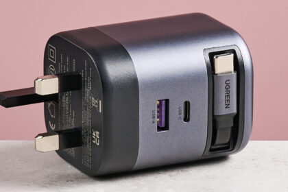 UGreen Nexode 65W Charger with Retractable USB-C Cable on its side against pink background