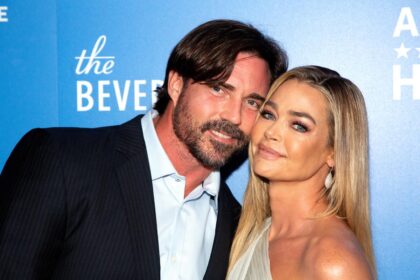 Denise Richards and Aaron Phypers share a warm embrace on the red carpet, smiling for photographers before the event.