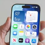 A person holding an iPhone running iOS 26.