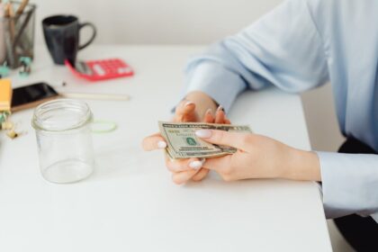A person in a blue shirt holding cash on a desk
