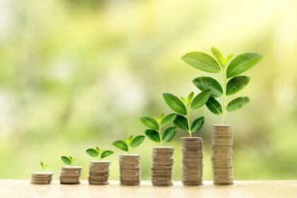 Stacks of coins growing with green shoots symbolizing financial growth and wealth building