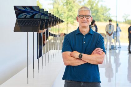 Apple CEO Tim Cook standing next to a row of MacBook Air laptops at the company's Worldwide Developers Conference (WWDC) in 2022.