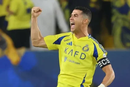 Cristiano Ronaldo celebrating a goal for Al-Nassr, raising his arms in triumph during a Saudi Pro League match.