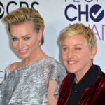 Ellen DeGeneres and Portia de Rossi smiling together on the red carpet at a formal event.