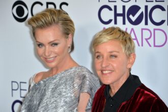 Ellen DeGeneres and Portia de Rossi smiling together on the red carpet at a formal event.