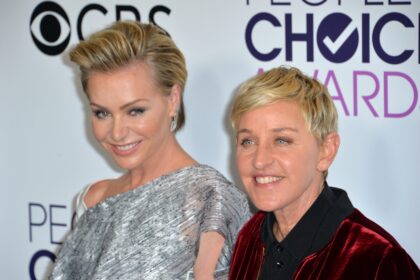 Ellen DeGeneres and Portia de Rossi smiling together on the red carpet at a formal event.