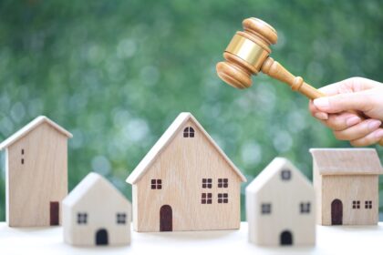property auction, woman hand holding gavel wooden and model house on natural green background, lawyer of home real estate and ownership property concept
