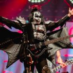 Gene Simmons on stage with arms wide, showing bat-winged costume.