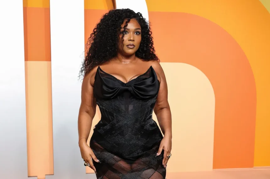 Lizzo posing on the red carpet in a sparkling gown, smiling confidently at photographers.