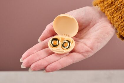A woman is holding the Loop Switch 2 earplugs in their case in her outstretched hand.