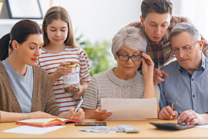 Three generations of a family sitting together at a table reviewing financial documents and discussing wealth planning.