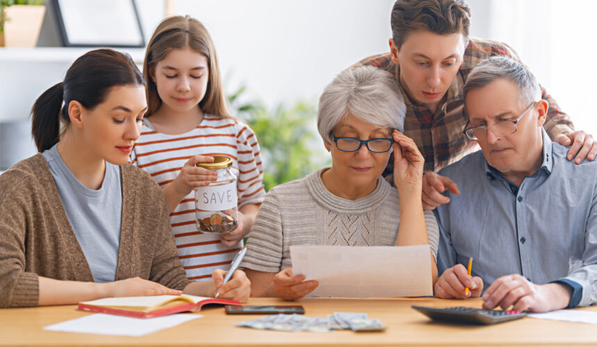 Three generations of a family sitting together at a table reviewing financial documents and discussing wealth planning.