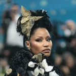 Nicki Minaj looking serious and glum on the red carpet, wearing a glamorous outfit.