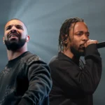 Kendrick Lamar and Drake performing together on stage, each with a microphone, under bright concert lights with an energetic crowd in the background.