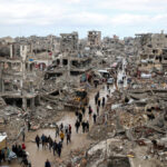 Palestinian families returning to their homes in Gaza, walking through streets filled with rubble and destroyed buildings after the conflict.