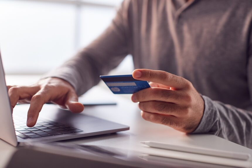close up of businessman working late on laptop at desk making online payment with credit card