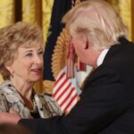 Donald Trump and Education Secretary Linda McMahon embrace on stage after announcing the renewed student loan forgiveness deal.