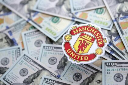Manchester United badge surrounded by floating US dollar bills, symbolizing the club's wealth.