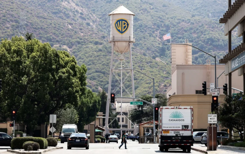 View of the Warner Bros. studio lot in Burbank, California, featuring the iconic WB water tower against the backdrop of the Hollywood Hills.